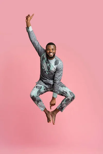 Захоплений чорний чоловік стрибає над рожевим тлом — стокове фото