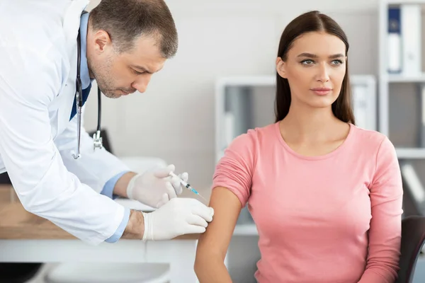 Зрілий лікар робить вакцинацію молодій жінці — стокове фото