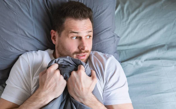 Hombre asustado acostado en la cama en casa por la noche — Foto de Stock