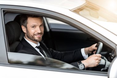 Neşeli başarılı iş adamı araba camından bakıyor.