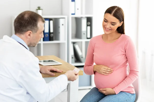 Mature experienced doctor giving pills to pregnant patient — Stock Photo, Image