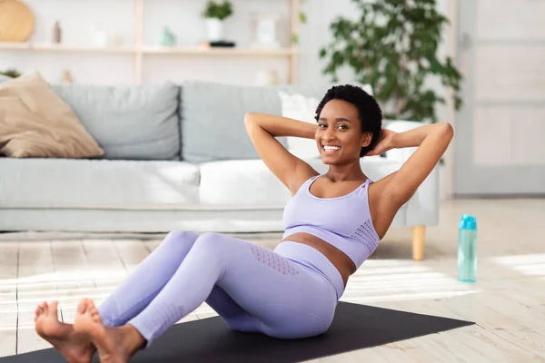 Positive athletische schwarze Frau macht Bauchmuskelübungen während ihres Heimtrainings, drinnen — Stockfoto