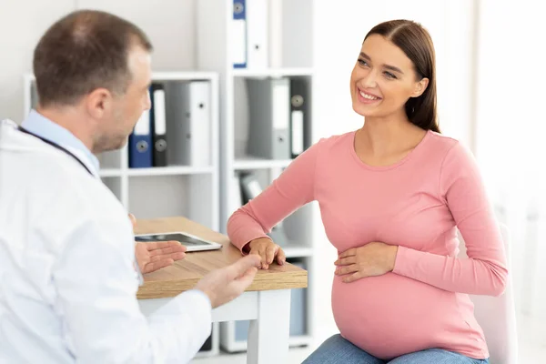 Male doctor consulting young smiling pregnant woman — Stock Photo, Image