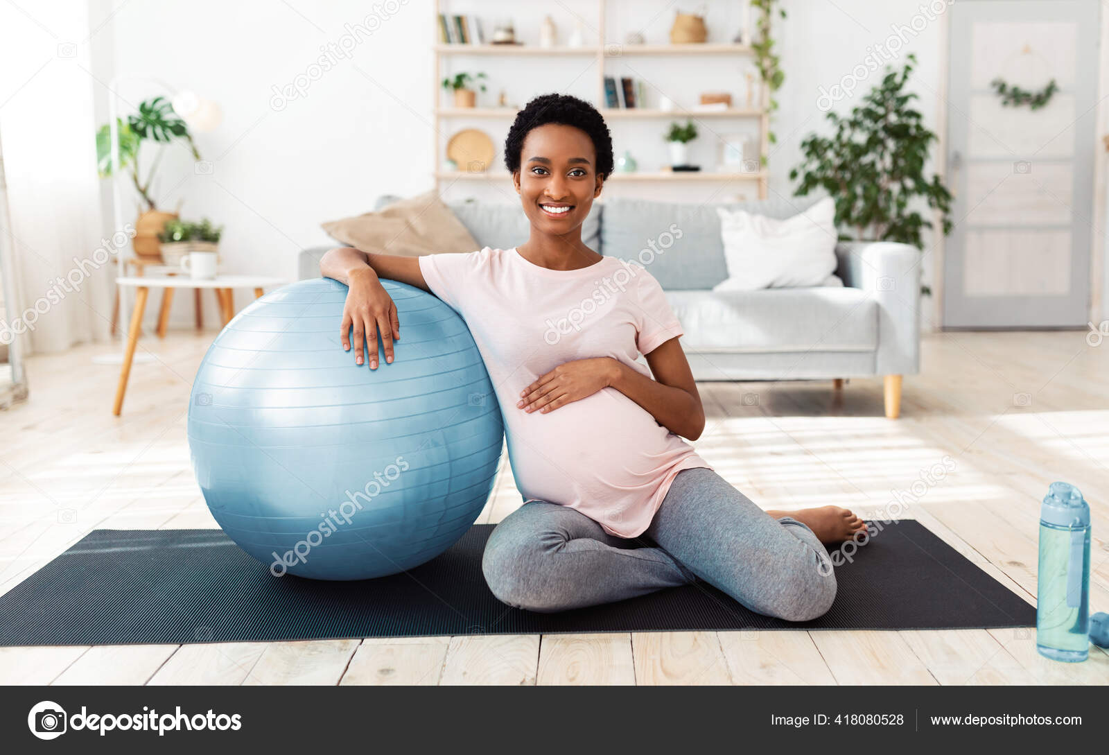 Exercising during pregnancy. Full length portrait of happy expectant woman sitting on yoga mat with fitness ball Stock Photo Milkos 418080528