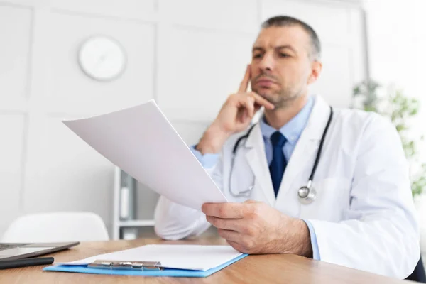 Portret dojrzałego lekarza czytającego raport medyczny — Zdjęcie stockowe