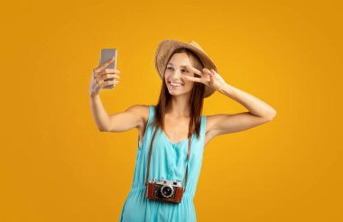 Güzel genç bayan gezgin cep telefonuyla selfie çekiyor.