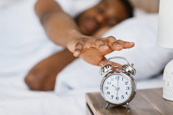 Africano despertando apagando despertador acostado en la cama —  Fotos de Stock