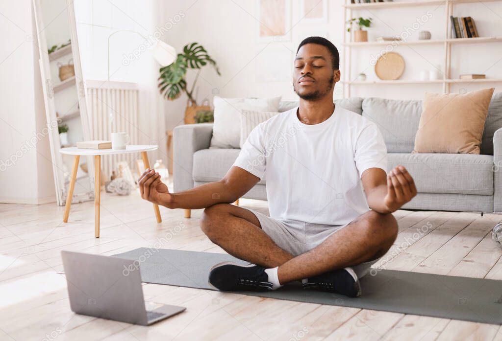 Black Man Meditating Doing Yoga Sitting At Laptop At Home