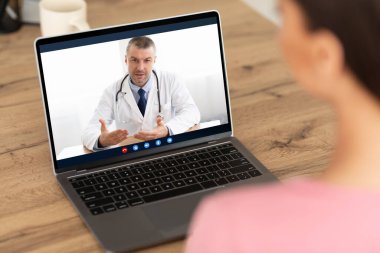Kadın, evdeki bilgisayarında doktorla görüntülü konuşma yapıyor.