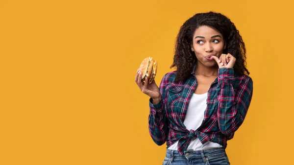 Feliz dama afroamericana sosteniendo hamburguesa en el estudio — Foto de Stock