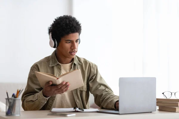 Koncentrált tizenéves diák headset olvasás tankönyv alatt online lecke laptop otthon, üres hely — Stock Fotó