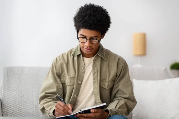 Ocupado chico adolescente afroamericano trabajando en proyecto educativo en casa — Foto de Stock