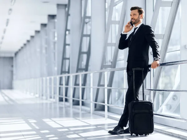 Empresário rico feliz em pé no aeroporto, falando no telefone celular — Fotografia de Stock