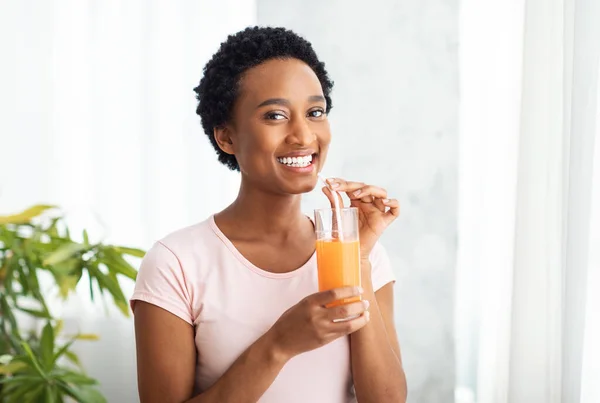 Note di alimentazione, dieta e disintossicazione. Bella donna afroamericana che beve succo d'arancia fresco a casa, spazio copia — Foto Stock