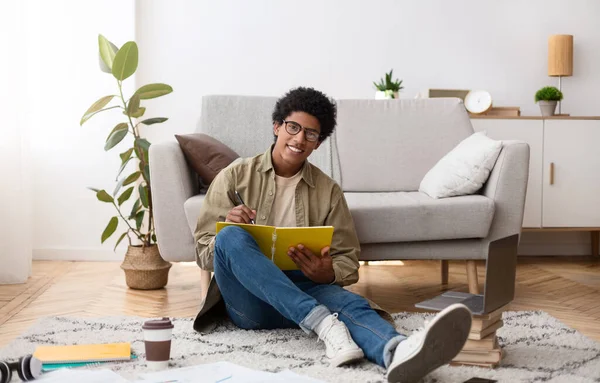Retrato de comprimento total de adolescente preto feliz escrevendo informações durante a palestra on-line sobre laptop, dentro de casa — Fotografia de Stock