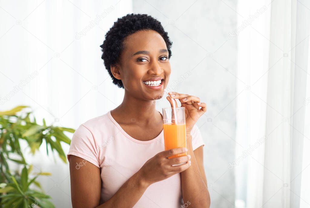 Healthy eating, dieting and detox. Pretty African American woman drinking fresh orange juice at home, copy space