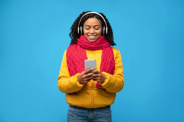 Αφρικανική γυναίκα στα ακουστικά κρατώντας τηλέφωνο ακούγοντας μουσική στο στούντιο — Φωτογραφία Αρχείου