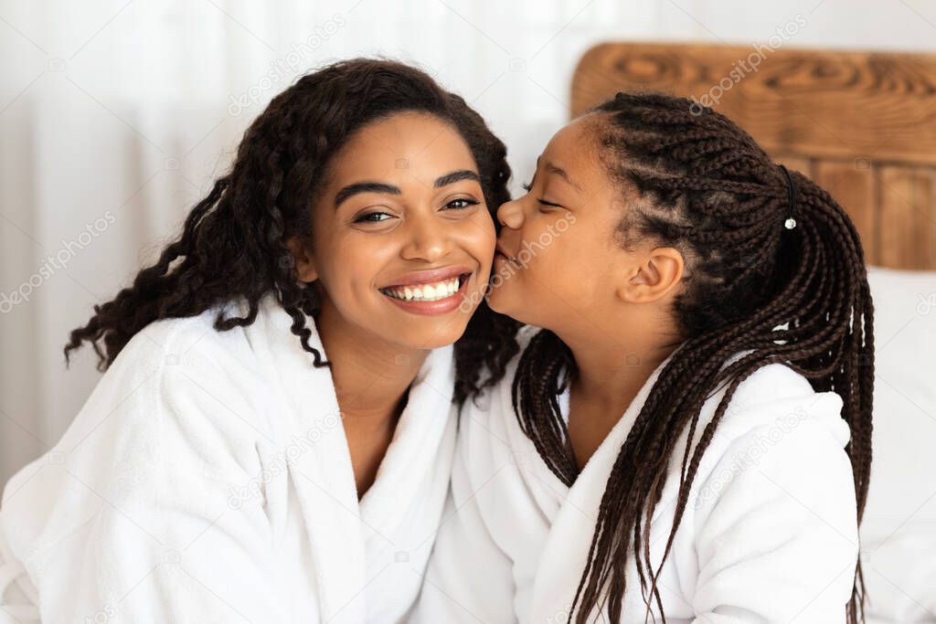 Little Black Girl Kissing Mom While They Relaxing In Bathrobes At Home