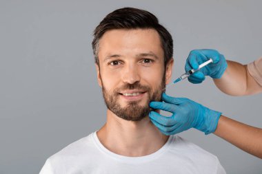 Çekici orta yaşlı adam kuaförde yaşlanma karşıtı prosedür uyguluyor.