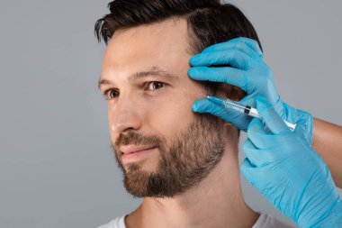 Plastik cerrah orta yaşlı bir adam için yüz dolgusu yapıyor.