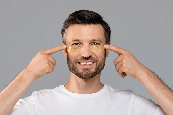 Souriant homme attrayant mettre des patchs sur son visage — Photo