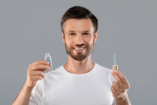 Hombre apuesto de mediana edad sosteniendo la botella con suero — Foto de Stock