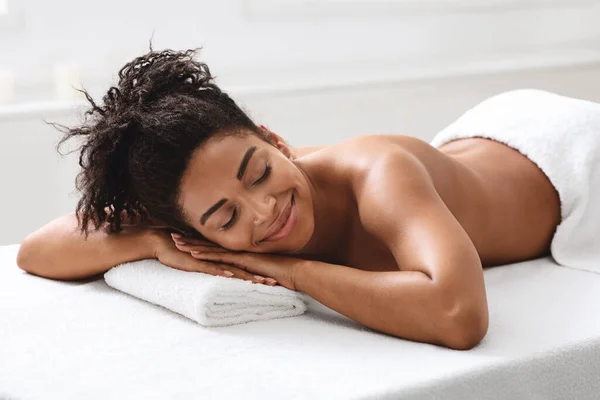 Avslappnad afrikansk amerikansk kvinna vilar efter helande massage — Stockfoto
