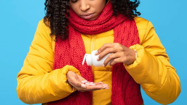 Enfermo africano señora tomando píldoras sosteniendo la botella de medicina, fondo azul —  Fotos de Stock