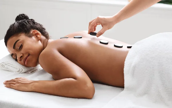 Весела чорна леді має гарячий кам'яний масаж в розкішному спа-центрі — стокове фото