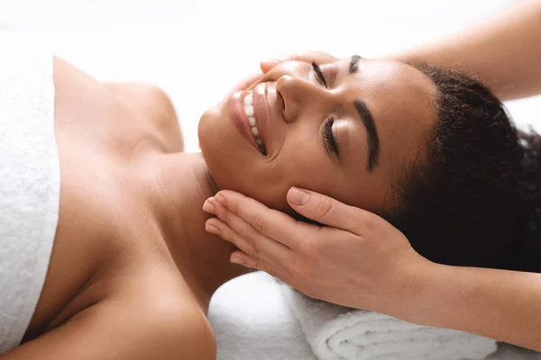 Sorrindo mulher negra ter levantando massagem facial no spa — Fotografia de Stock