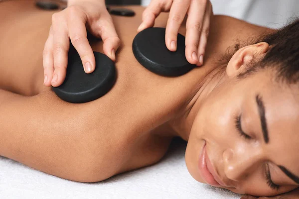Närbild av svart dam som har läkande varm sten massage — Stockfoto