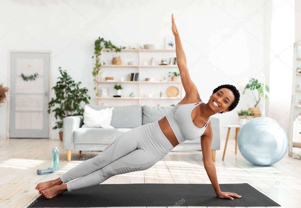 Young African American woman doing strength exercises on mat in living room