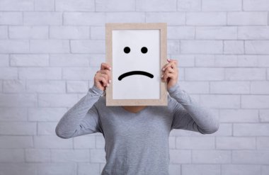 Depresyon, üzüntü, olumsuz duygu konsepti. Yüzünde hüzünlü bir ifade olan çerçeveyi tutan genç bir kadın.