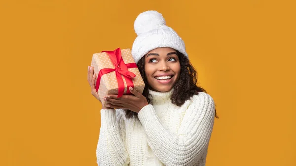 Mujer afroamericana sacudiendo regalo de Navidad en el estudio —  Fotos de Stock