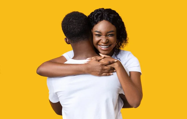 Mulher negra emocional abraçando seu namorado e sorrindo para a câmera — Fotografia de Stock
