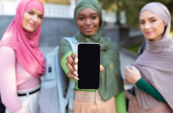 Tres mujeres musulmanas mostrando la pantalla del teléfono inteligente al aire libre, se centran en el teléfono —  Fotos de Stock