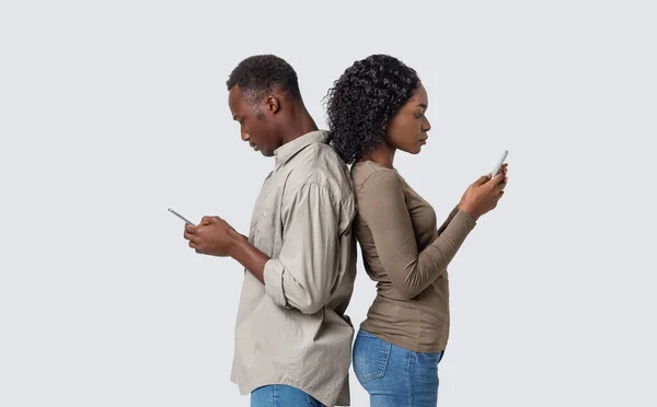 Africano homem e mulher de pé de volta para trás, usando celulares — Fotografia de Stock