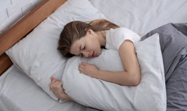 Depresyondaki genç bir kadının yatakta yatıp yastığına sarılışının en üst görüntüsü.