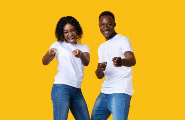 Oynayan genç siyah çift flört ediyor, kameraya parmak tabancalarını gösteriyorlar.