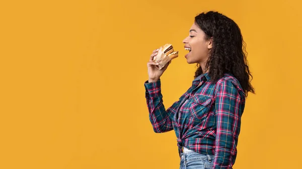 Divertente afroamericano signora mangiare hamburger a studio — Foto Stock