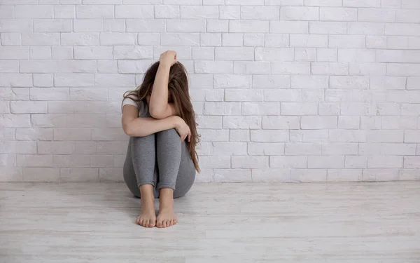 Desesperada jovem chorando de desesperança no chão perto da parede branca, espaço em branco — Fotografia de Stock