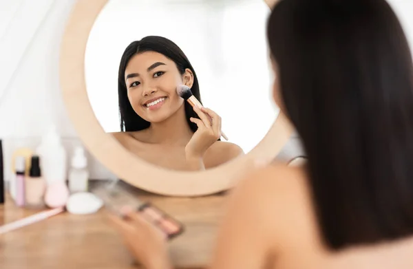 Atraente sorrindo asiático mulher aplicando blush no seu rosto — Fotografia de Stock