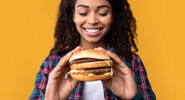 Closeup de engraçado preto senhora segurando hambúrguer no estúdio — Fotografia de Stock