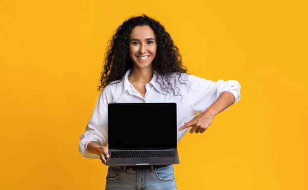 Mockup Imagem de uma jovem mulher segurando laptop, apontando para a tela do computador preto — Fotografia de Stock