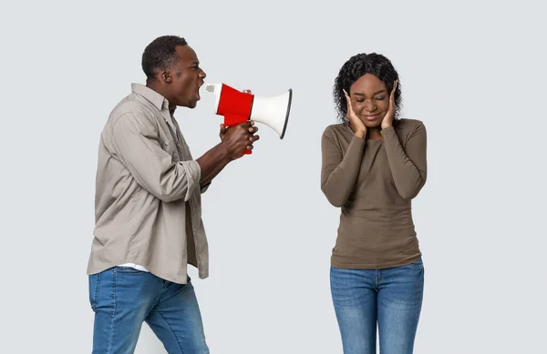 Angry african guy shouting through megaphone at his girlfriend — Stock Photo, Image