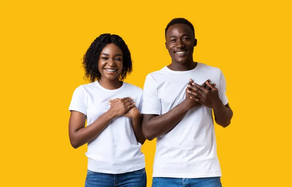 Freundliche Frau und Mann, die beide Handflächen auf der Brust halten — Stockfoto