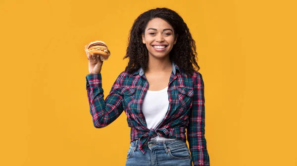 Funny afroamericana dama mostrando hamburguesa en el estudio — Foto de Stock