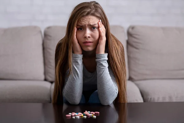 Emotional breakdown and suicide. Young lady with pills having psychological disorder and planning to kill herself