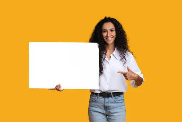 Lugar libre para el anuncio. Sonriente morena mujer señalando blanco en blanco placa — Foto de Stock