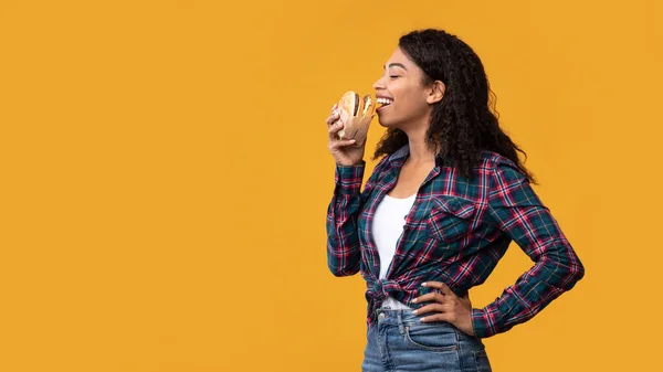 Divertida dama afroamericana comiendo hamburguesa en Orange Studio — Foto de Stock